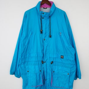 May include: A blue and pink vintage jacket with a drawstring hood and multiple pockets. The jacket has a black zipper and a black label that reads "Alpine Sportswear".