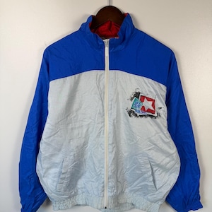 May include: A vintage blue, white, and red Starter jacket with a full zipper closure. The jacket features a color block design with blue sleeves and upper back, white midsection, and a red interior lining. A logo is on the front.