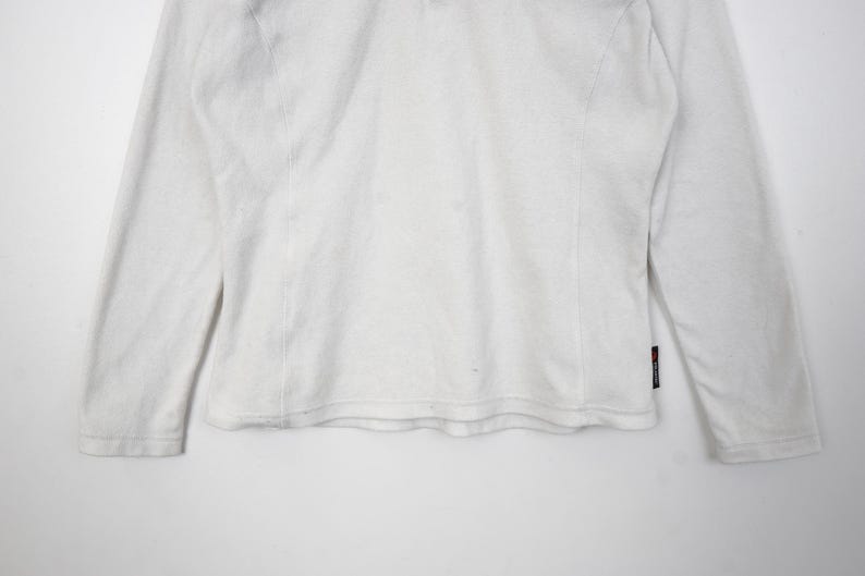 Op de afbeelding: Wit shirt met lange mouwen. Het shirt heeft een ronde hals en een eenvoudig ontwerp. De mouwen zijn lang en eindigen bij de polsen. Het shirt is gemaakt van een zacht, comfortabel materiaal. Het shirt is effen wit.