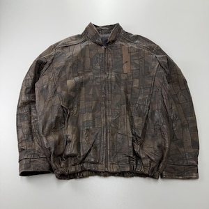 Könnte beinhalten: Eine dunkelbraune Lederjacke mit einem Patchwork-Design aus verschiedenen rechteckigen und quadratischen Lederstücken. Die Jacke verfügt über einen durchgehenden Frontreißverschluss, einen Stehkragen, lange Ärmel mit Bündchen und einen elastischen Saum.