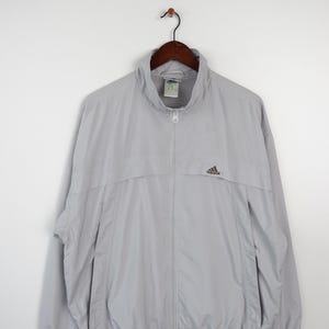 May include: A light gray zip-up jacket with a small black Adidas logo on the left chest.