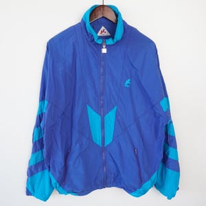 May include: A blue and turquoise windbreaker jacket with a white logo that says "Kangol Sport".