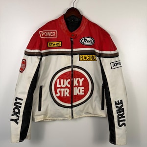 May include: A vintage racing jacket in red, white, and black, featuring multiple patches with text like "POWER," "STARS," and "LUCKY STRIKE." The jacket has a zip-up front and a classic motorcycle style.