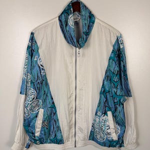 May include: A set of three ceramic mugs with a speckled, cream-colored glaze. Each mug features a different hand-painted floral design in shades of blue, green, and yellow. The mugs have a simple, rounded shape and a comfortable handle.