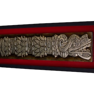 May include: A silver framed wall art piece with a red mat. The art features a silver relief sculpture of a stylized serpent with intricate details.