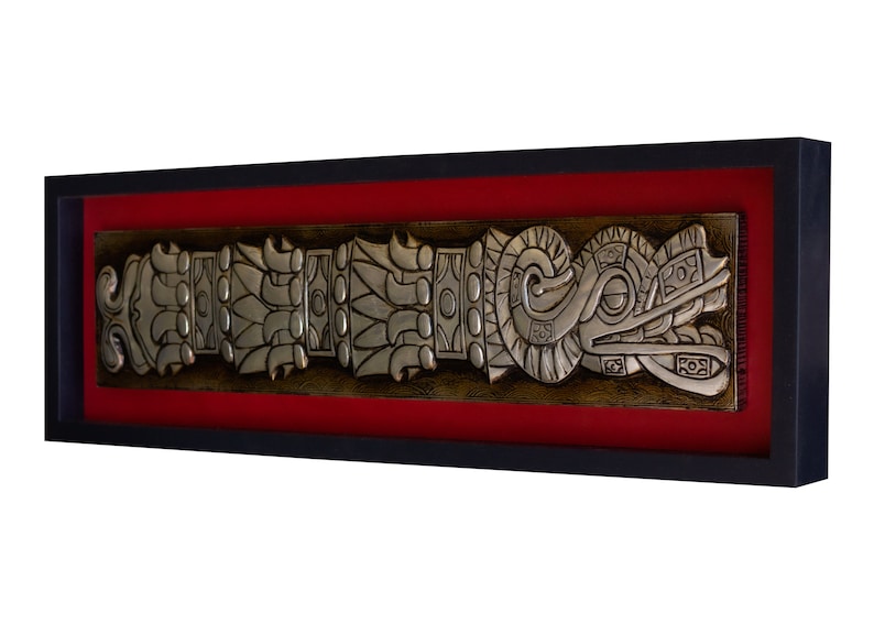 May include: A silver framed wall art piece with a red mat. The art features a silver relief sculpture of a stylized serpent with intricate details.
