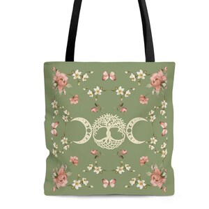 May include: A green tote bag with black handles features a floral pattern with white flowers, pink roses, and butterflies. The center of the bag has a white triple moon symbol with a tree of life inside.
