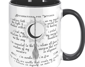 May include: White ceramic mug with a black interior and handle. The mug features a crescent moon, broom, and sun design with text that reads "Affirmations for Witches". The mug is a perfect gift for anyone interested in witchcraft.