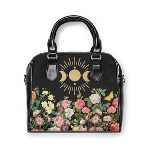 May include: Black handbag with a floral print and a gold moon and sun design.