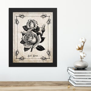 May include: Black and white vintage illustration of roses with the text "Sub Rosa" on a beige background. The image is framed in black.