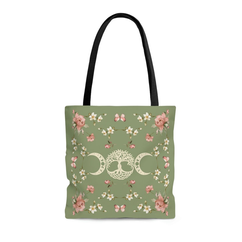 May include: A green tote bag with black handles features a floral pattern with white flowers, pink roses, and butterflies. The center of the bag has a white triple moon symbol with a tree of life inside.