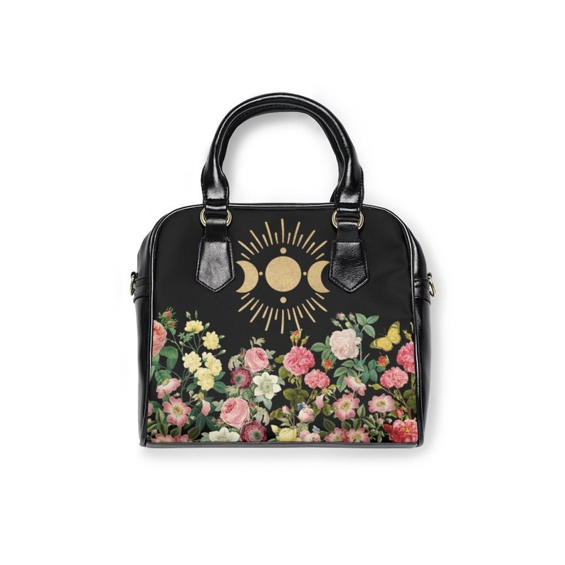 May include: Black handbag with a floral print and a gold moon and sun design.