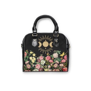 May include: Black handbag with a floral print and a gold moon and sun design.