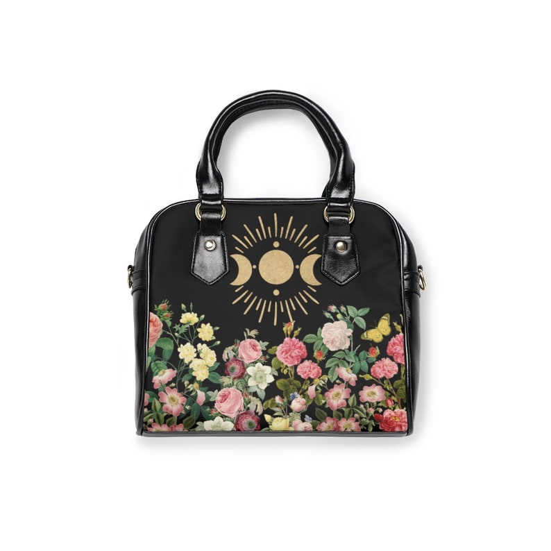 May include: Black handbag with a floral print and a gold moon and sun design.