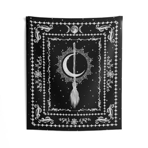May include: Black and white tapestry with a crescent moon and a broom in the center. The design is surrounded by a decorative border with floral motifs and stars.