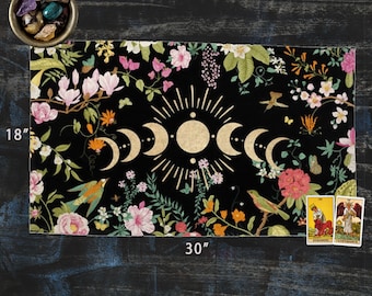 Op de afbeelding: Een zwart en gouden wandkleed met een bloemenpatroon en een maanfasenontwerp. Het wandkleed is 76 cm breed en 46 cm hoog.
