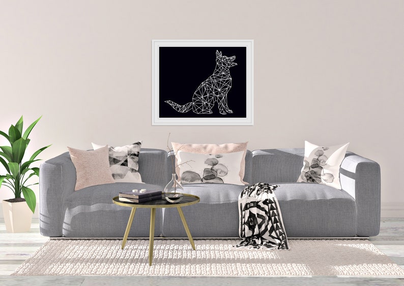 May include: A gray sofa with a black and white geometric throw blanket and three pillows. The pillows are pink, black and white, and gray with a black and white watercolor design. A black and white geometric illustration of a dog is hanging on the wall above the sofa.