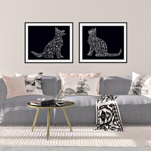 May include: Two black and white geometric animal illustrations in frames, a dog and a cat, hanging above a gray couch with pillows and a throw blanket.
