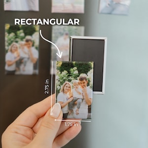 A hand holding a small rectangular magnet with a photo of a family on it, along with measurements indicating the magnet is approximately 1.75 inches in size.