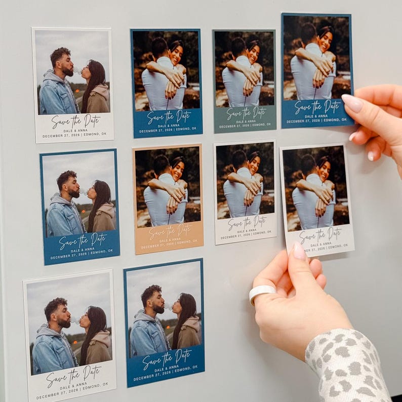 a person's hands arranging a collection of wedding invitation cards on a wall.