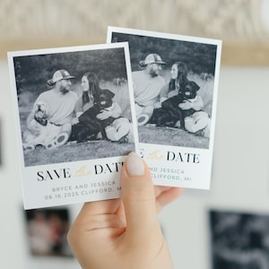 May include: Two save the date cards with black and white photos of a couple with their dogs. The text on the cards reads "Save the Date" and includes the couple's names, wedding date, and location.