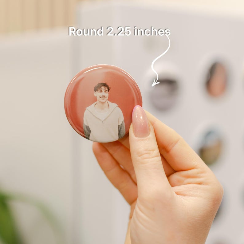 A person's hand holding a round pin with a photo of a man on it, and the text "Round 2.25 inches" indicating the size of the pin.