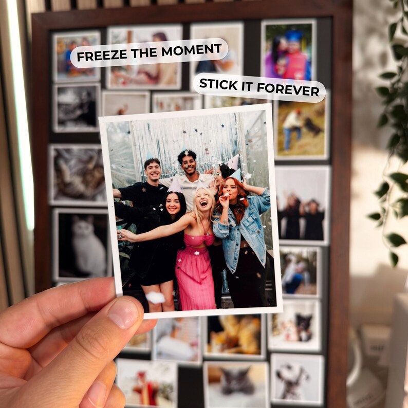 A hand holding a Polaroid-style photo of a group of people, with the text "FREEZE THE MOMENT STICK IT FOREVER" overlaid on the image.