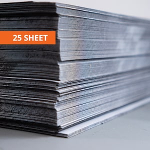 May include: A stack of silver-colored sheets of paper. The sheets are stacked neatly, with the edges aligned. An orange rectangle with the text "25 SHEET" is visible on the left side of the image. The paper has a metallic sheen.