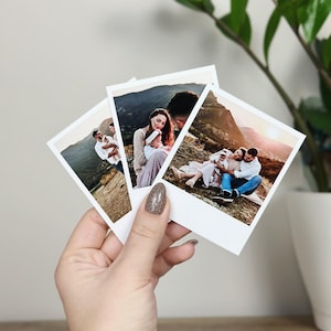 May include: Three square instant film prints featuring outdoor family portraits. Each photograph displays a different scene of a family with a small child in a mountainous landscape during sunset, characterised by warm lighting and natural tones.