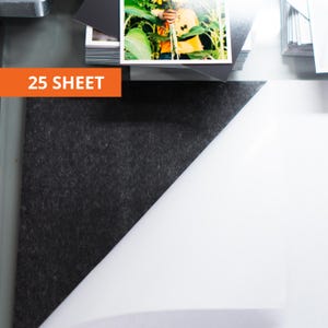 May include: A 25 sheet pack of paper featuring a dark charcoal gray textured side and a smooth white side. The sheets are stacked, with the top sheet partially folded to reveal both contrasting surfaces. A photograph is visible at the top.