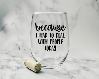 May include: A clear stemless wine glass with black text that reads "because I HAD TO DEAL WITH PEOPLE TODAY". A cork rests near the glass. The background is a white and gray marble pattern.