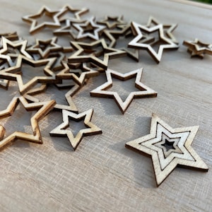 Peut inclure: Un tas d'étoiles en bois naturel de différentes tailles, éparpillées sur une surface en bois clair.