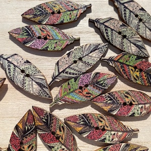 Peut inclure: Assortiment de boutons en bois colorés en forme de plumes avec des motifs complexes. Les boutons ont deux trous chacun et sont parfaits pour les projets de bricolage et de couture.