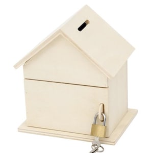 Può includere: Un salvadanaio di legno a forma di casa con uno slot sul tetto e una serratura e una chiave sul davanti.