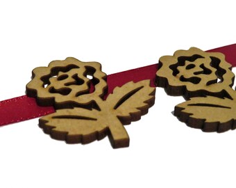 Puede incluir: Primer plano de una guirnalda artesanal de madera con una cinta roja. La guirnalda presenta múltiples rosas de madera recortadas con hojas.