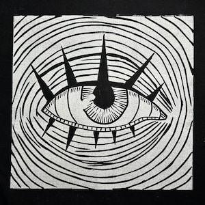 May include: A black and white illustration of a stylized eye with radiating lines and a circular pattern in the background.