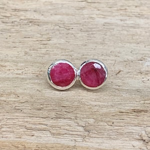 May include: A pair of silver stud earrings with round, pink gemstones.
