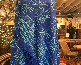 May include: A blue and green patterned sarong with fringe on the bottom edge. The sarong is draped over a mannequin.