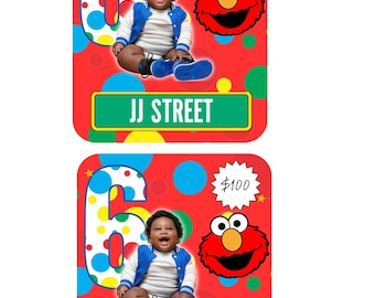 May include: Two rectangular cards with a red background featuring colorful polka dots. Each card displays a large number 6, a photo of a baby in a blue and white jacket, a red Elmo character, a white starburst with $100, and a green sign reading JJ STREET.