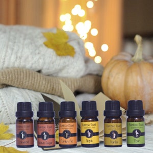 Könnte beinhalten: Sechs kleine braune Glasflaschen mit Etiketten, auf denen "Bamboo Road Essential Oils" und verschiedene Herbstdüfte stehen: Teakholz, brauner Zucker, Kürbiskuchen, Apfel, Vanille und Birne.