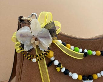 Handmade bag accessory featuring a natural orchid with details of bees and wildflowers.