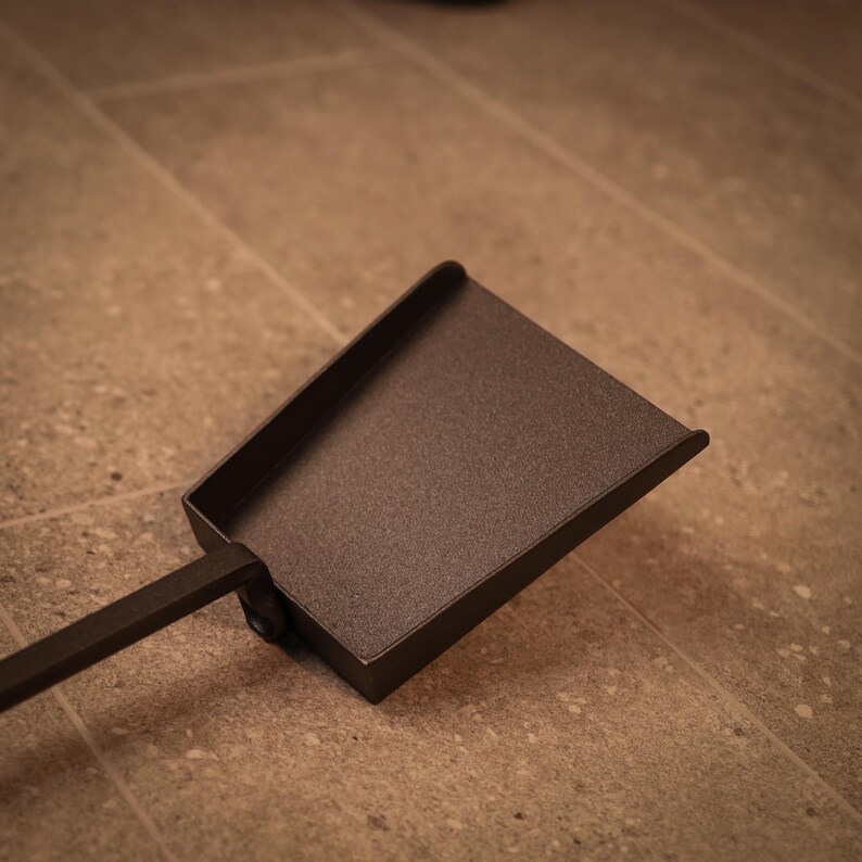 May include: A black metal fireplace shovel with a long handle.