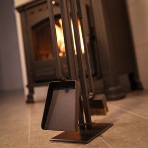 May include: A black metal fireplace tool set with a shovel, poker, tongs, and brush. The tools are mounted on a stand with a black metal base.