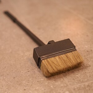 May include: A black fireplace brush with a long wooden handle and a rectangular brush head with natural bristles.
