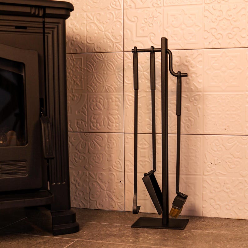 May include: Black metal fireplace tool set with a stand. The set includes a poker, shovel, and brush.