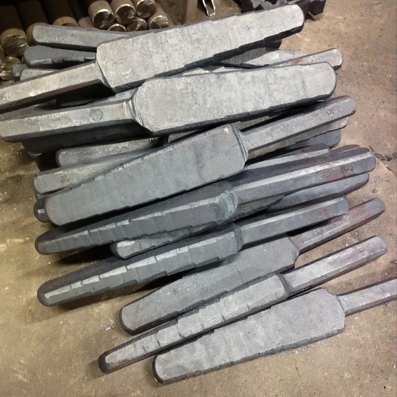 May include: A pile of gray metal rods with a slightly pointed end. The rods are stacked on top of each other and are all the same size.