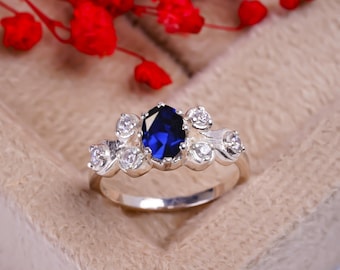 May include: A silver ring with a large blue oval gemstone surrounded by smaller white gemstones.