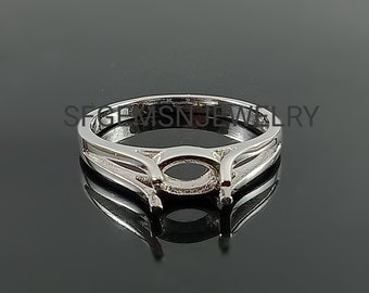 May include: Silver ring setting with a delicate, oval-shaped center for a gemstone. The ring band features a double-prong design.