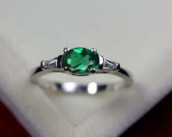 May include: A silver ring with a large oval-shaped green gemstone and two smaller accent stones.