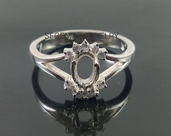 May include: Silver ring setting with an oval shaped center stone and a halo of small round stones.  The ring is designed with a split shank.